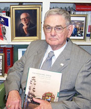 Dr. Archie McDonald posing with one of his books
