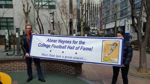 me and woman holding banner saying Abner Haynes for the College Football Hall of Fame