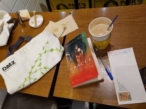 book on Delphic Oracle, coffee, pen, DMZ bag
