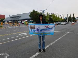 Song Woo-jin holding "Bring Jikji back to Korea" banner