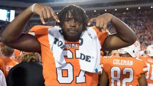 Oklahoma State football player doing Horns down sign